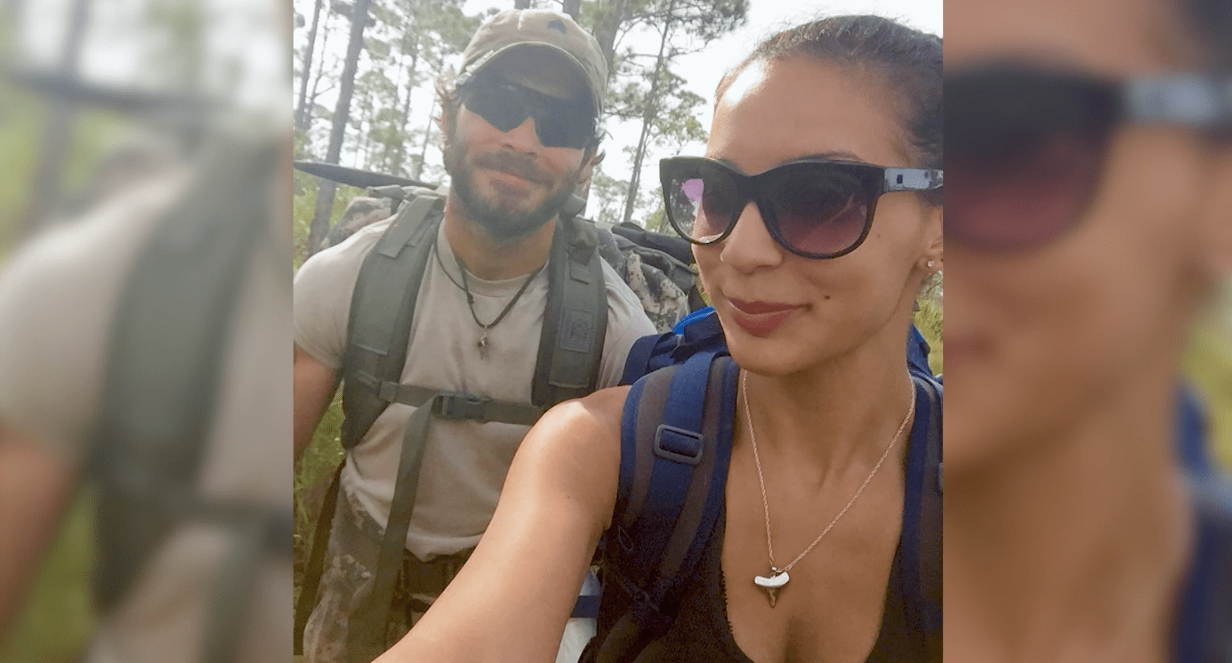 Two hikers taking a selfie on a forest trail, backpacks and sunglasses.